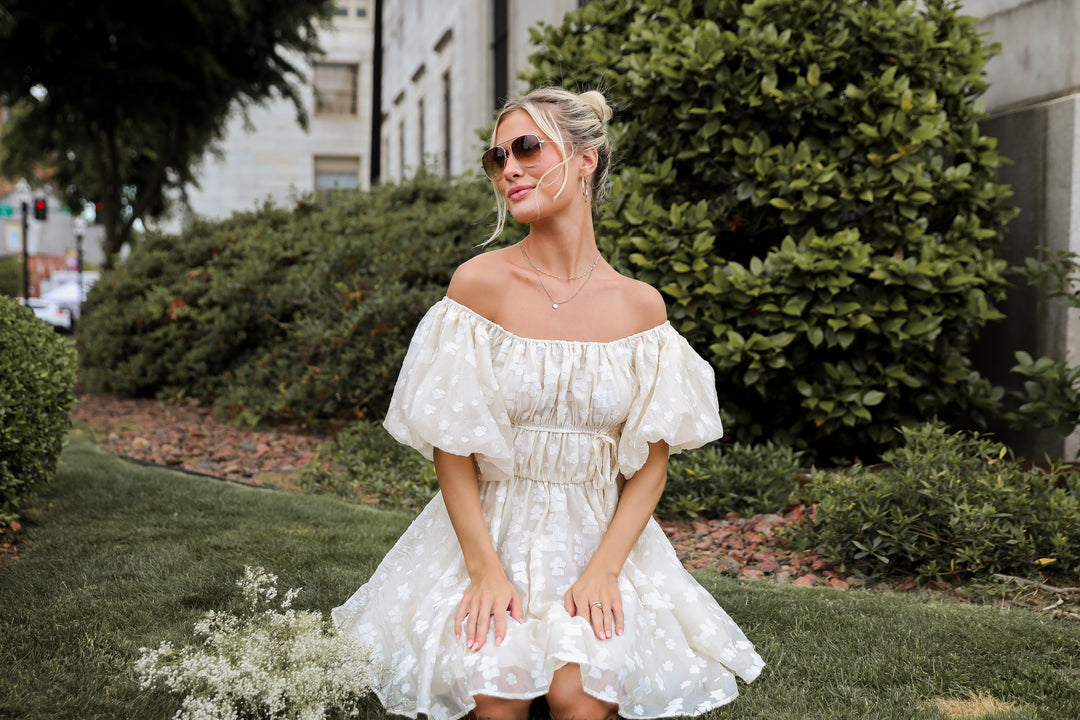 model wearing cute flowy puff sleeve cream floral mini dress